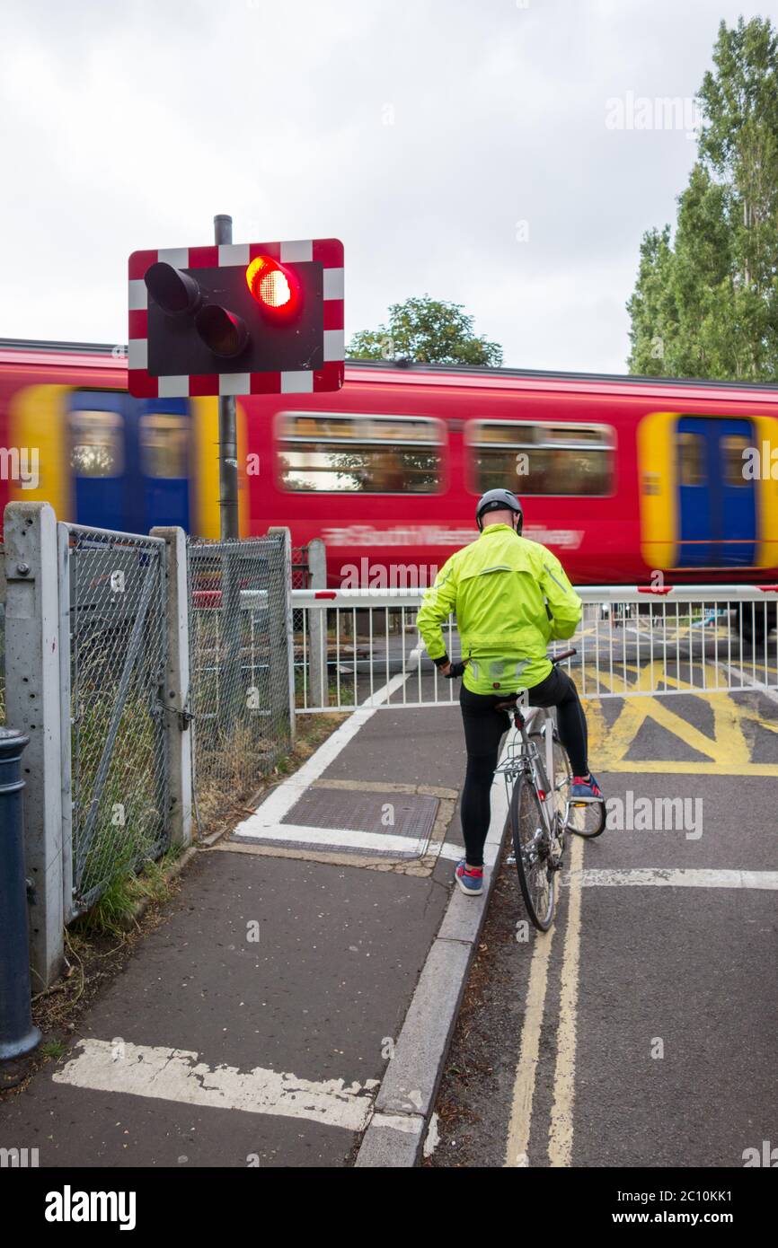 Un ciclista solitario en el cruce de nivel de Vine Road de Network Rail en Barnes, SW London, Reino Unido Foto de stock