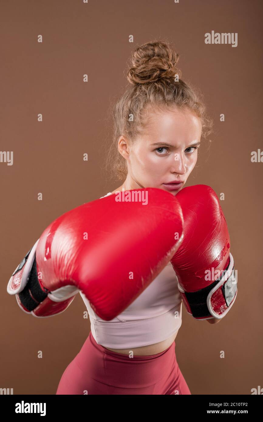 Deportiva mujer joven en guantes de boxeo rojos practicando golpes