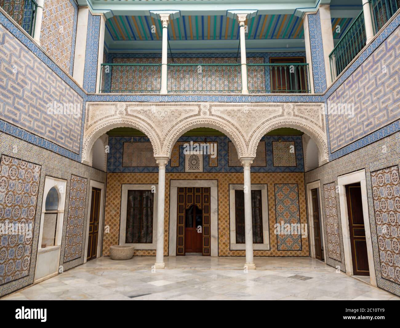 Patio de azulejos ornamentados de un palacio otomano restaurado en el corazón de la medina de Túnez con arcos de filigranas, suelos de mármol y diseños de azulejos variados. Foto de stock