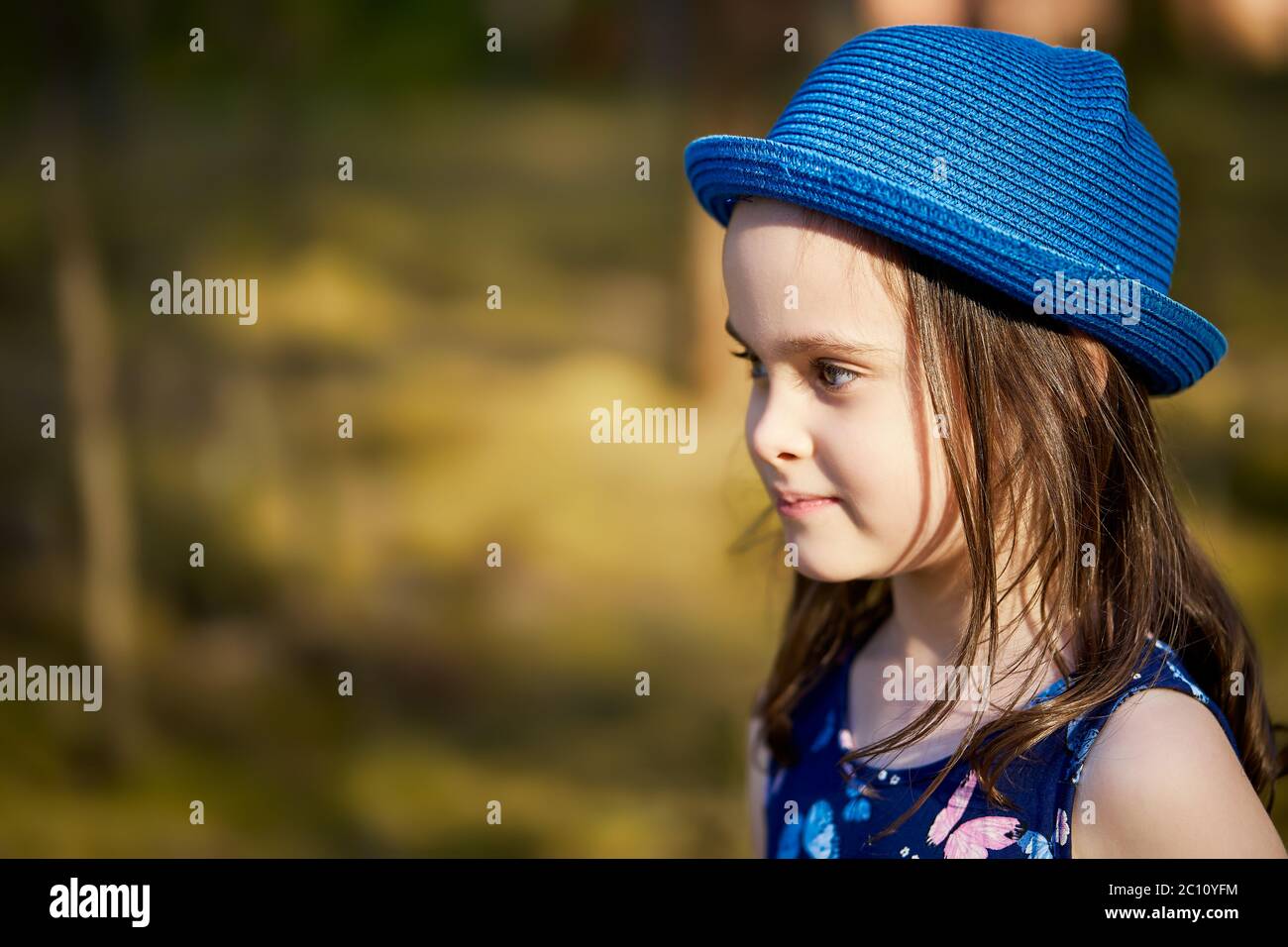 niña en un sombrero azul posando en el bosque de pinos de