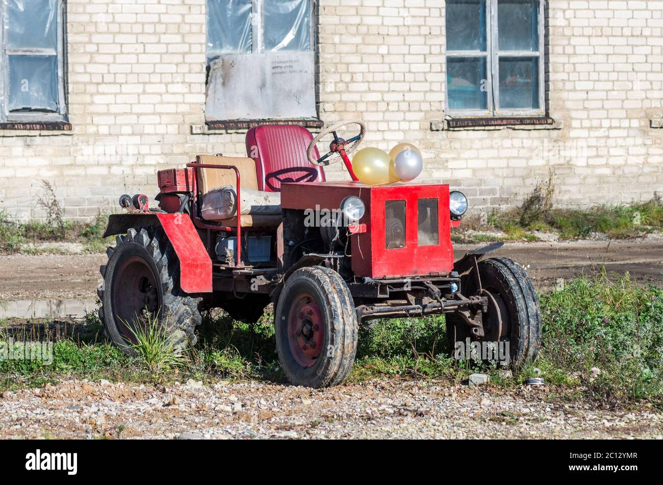 Viejo tractor rojo ruso en la pared izquierda Foto de stock