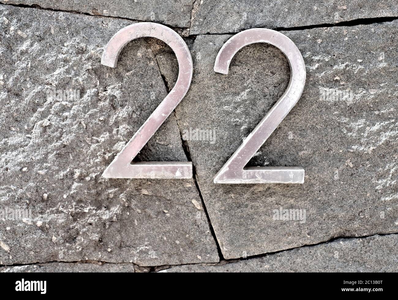 22, número veintidós, dígitos metálicos en la superficie de la piedra. Foto de stock