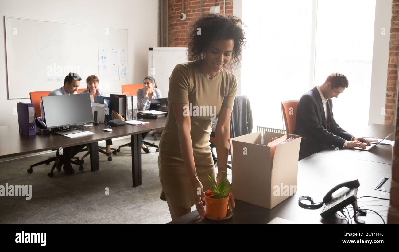 Feliz mujer de negocios afroamericana desempacando cosas en el nuevo trabajo Foto de stock