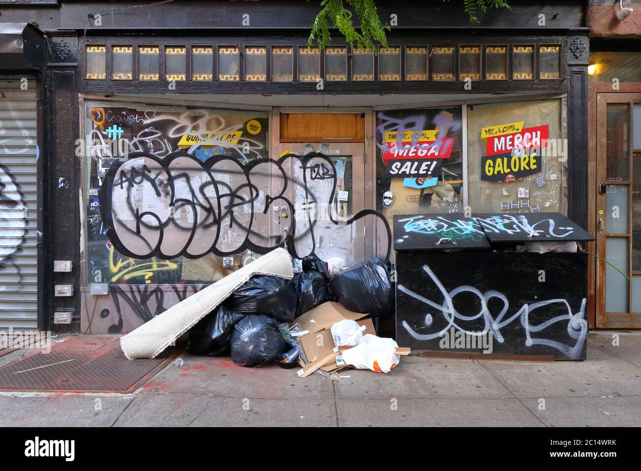 Graffiti y basura frente a un escaparate cerrado y no utilizado en Nueva York. Foto de stock