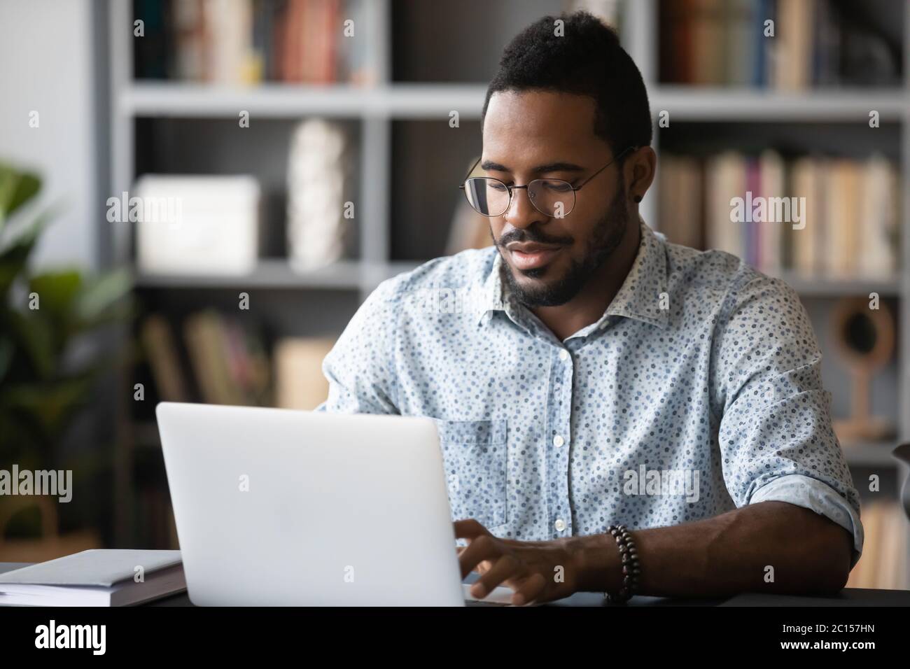 El hombre africano ocupado freelancer hacer el trabajo remoto usando el portátil Foto de stock
