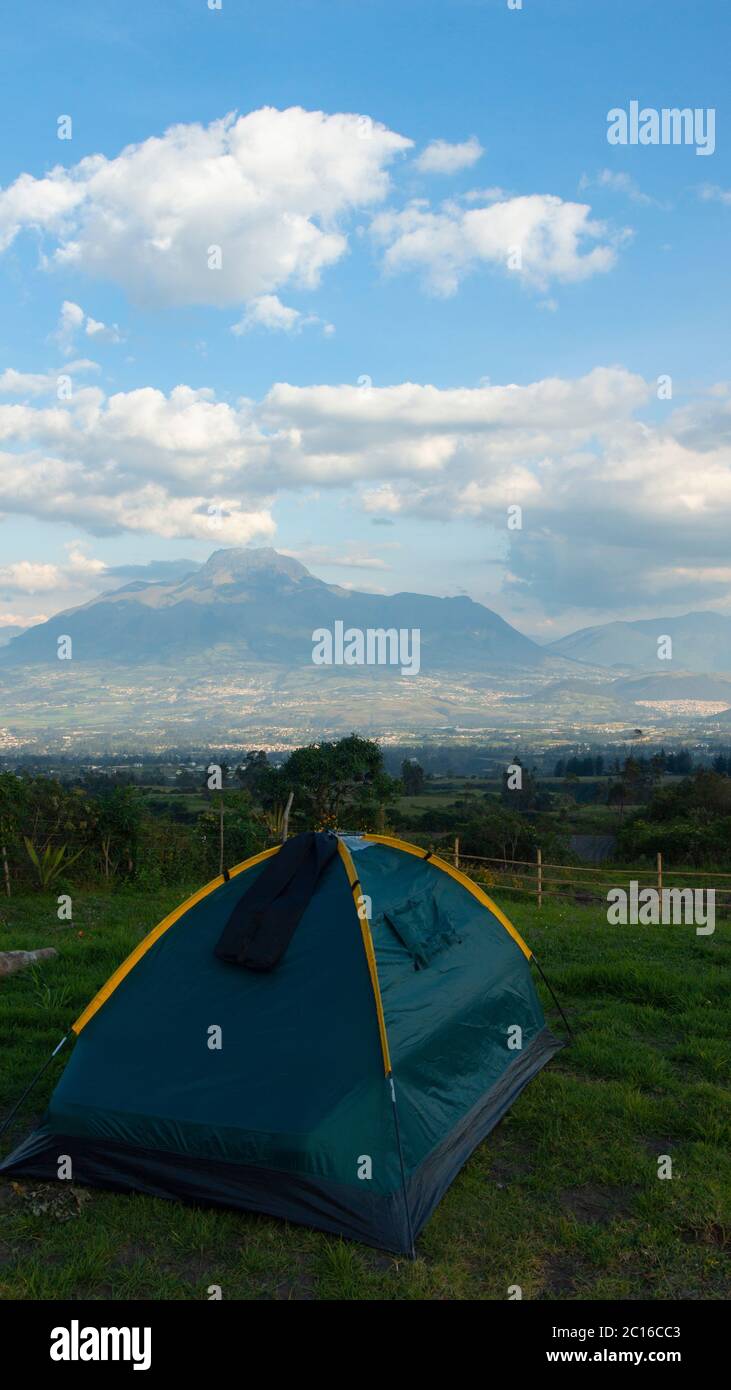 Tienda de camping verde en un campo de hierba con el volcán Imbabura en el fondo en un día nublado Foto de stock