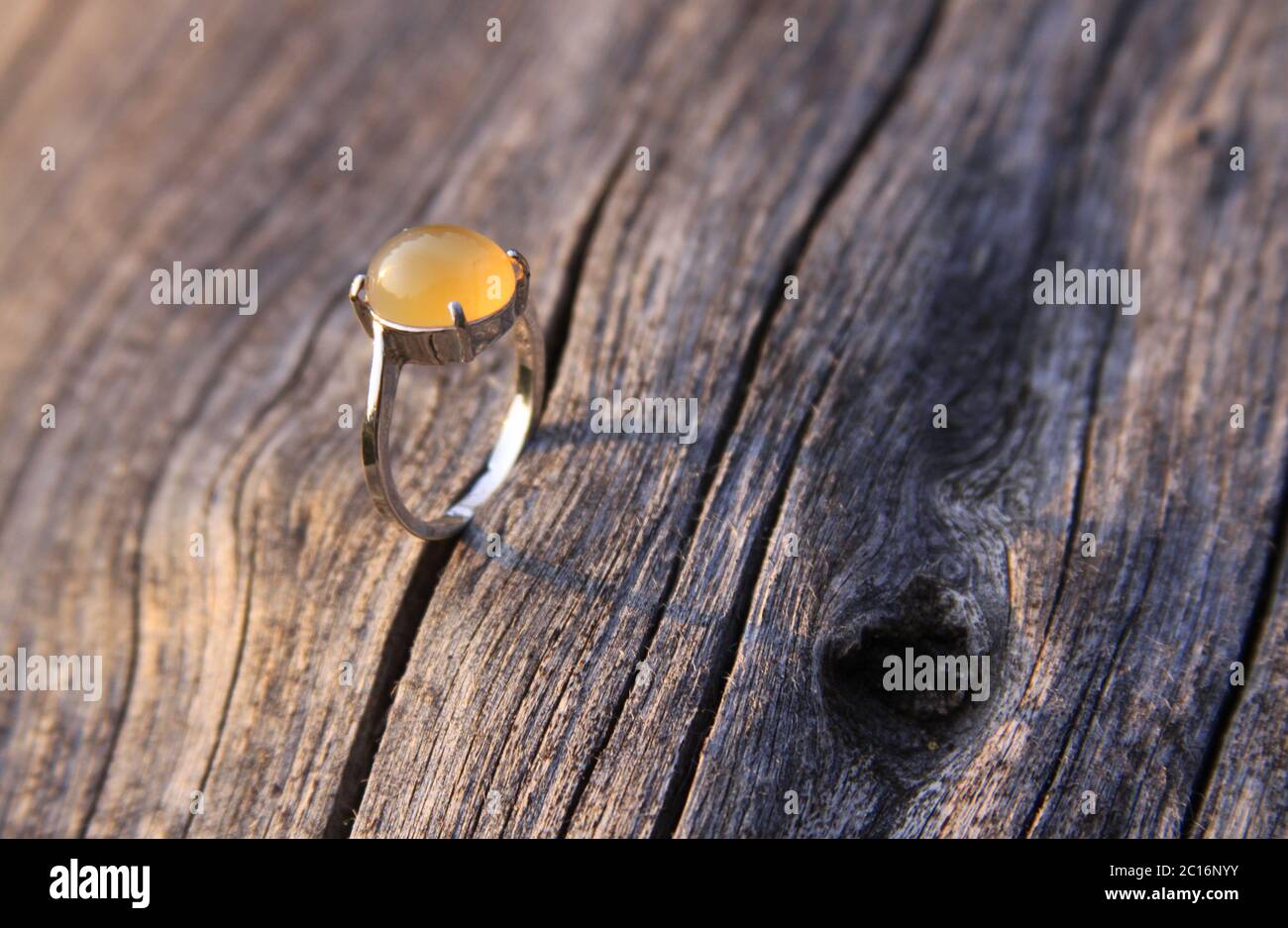 Anillo de compromiso con crema de color amarillo naranja calcedonia agate gemstone sobre madera. Las gemas de calcedonia vienen en una variedad de colores diferentes y son normalmente pol Foto de stock