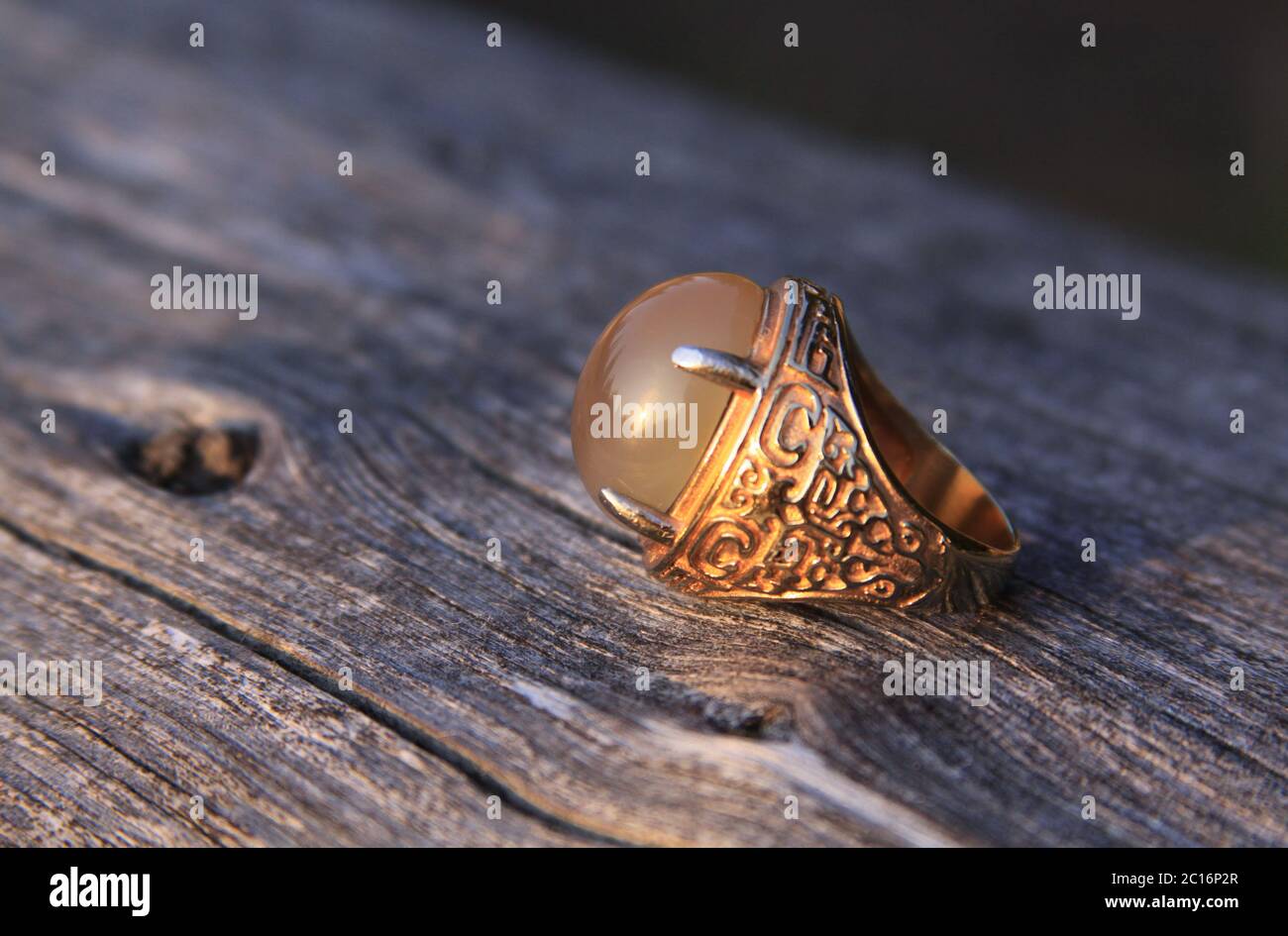 Hombres musulmanes aqeeq anillo de humor con calcedonia amarilla agate piedra preciosa sobre madera. Los machos islámicos de las culturas árabes usan anillos akik o aqiq en sus manos Foto de stock