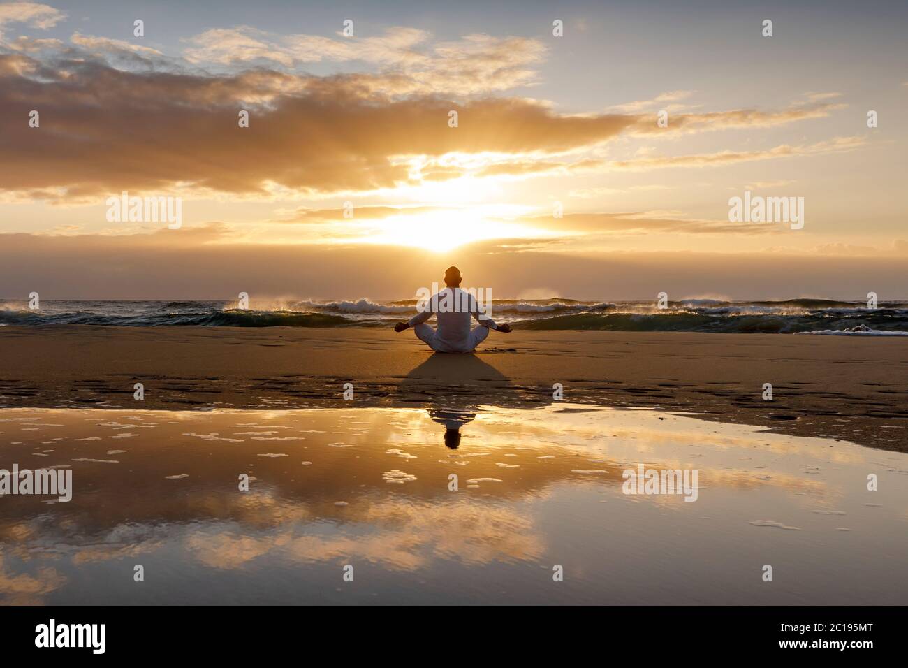 yoga meditación silueta lotus amanecer playa, atención, bienestar y concepto de bienestar, agua reflexión del hombre en yoga loto pose sentado solo Foto de stock