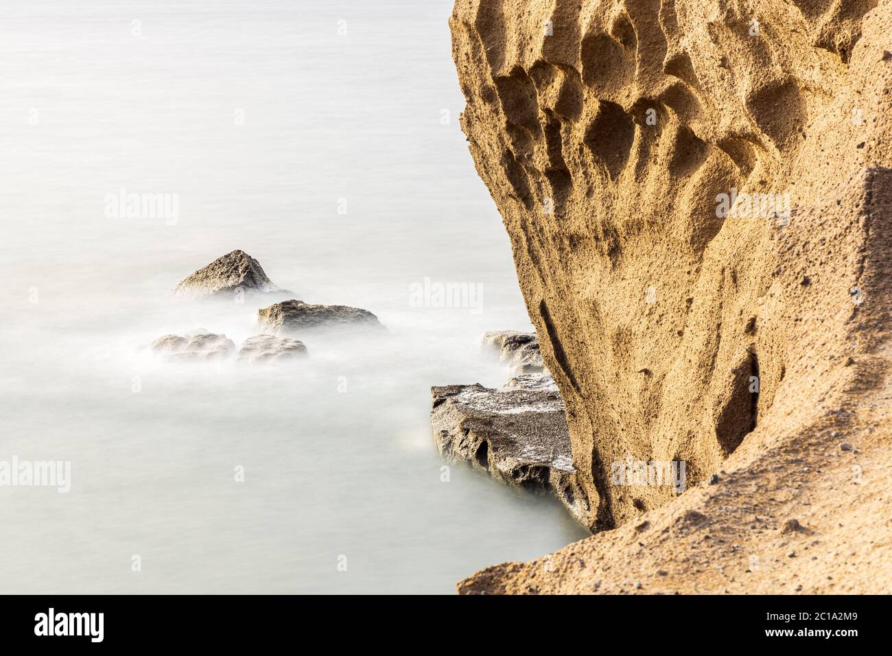 Fotografía de larga exposición con rocas de color arena en el océano atlántico en la costa por Tajao, Tenerife, Islas Canarias, España Foto de stock