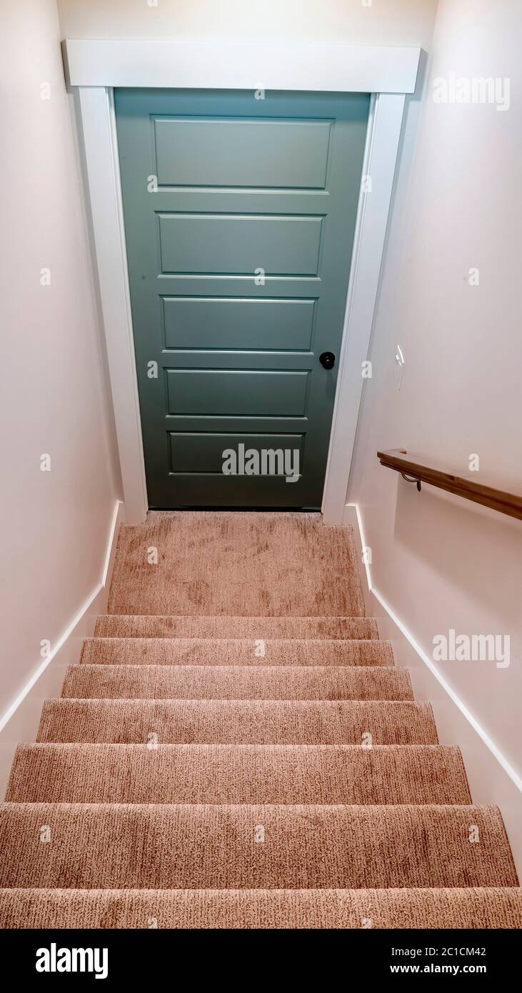 Escaleras interiores verticales de la casa con escalones alfombrados que  conducen a la puerta del sótano Fotografía de stock - Alamy