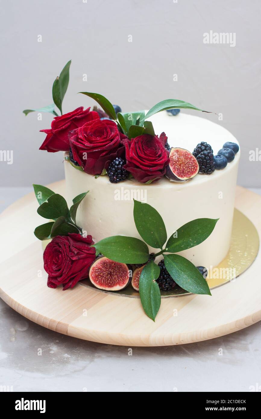 Elegante pastel de boda decorado con rosas rojas frescas, hojas verdes,  higos y arándanos. Fondo gris claro Fotografía de stock - Alamy