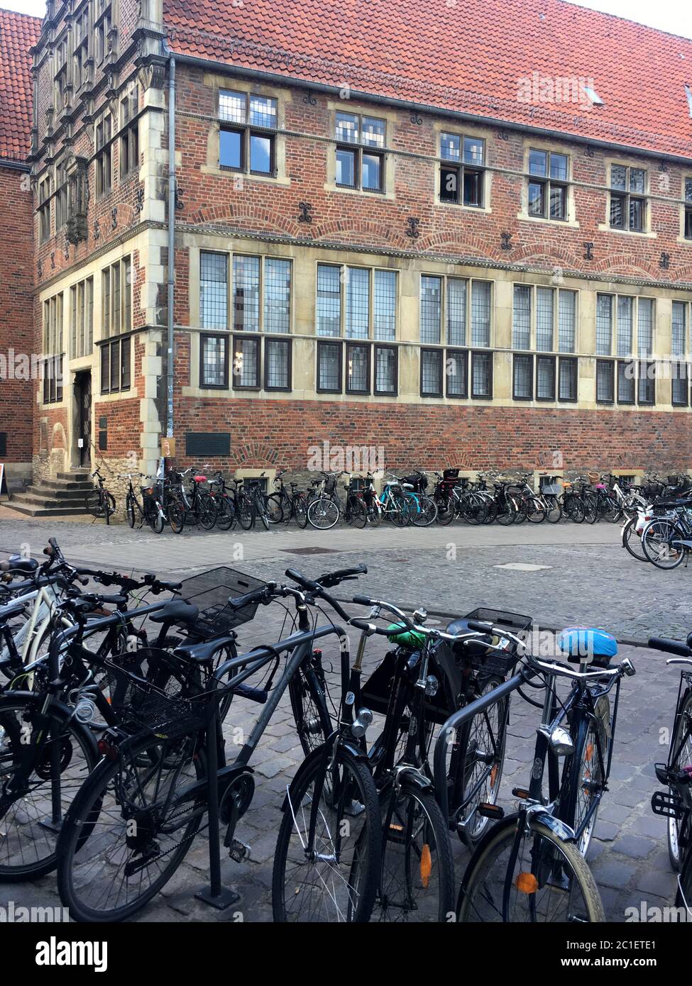 La antigua casa del clan y el edificio de la WWU Haus der Niederlande/ Krameramtshaus en Muenster, Alemania con muchas bicicletas estacionadas en frente. Foto de stock