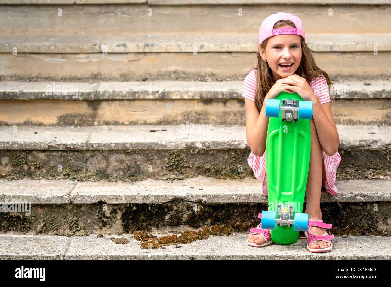 Chica con tabla de skate sentada en la escalera Foto de stock