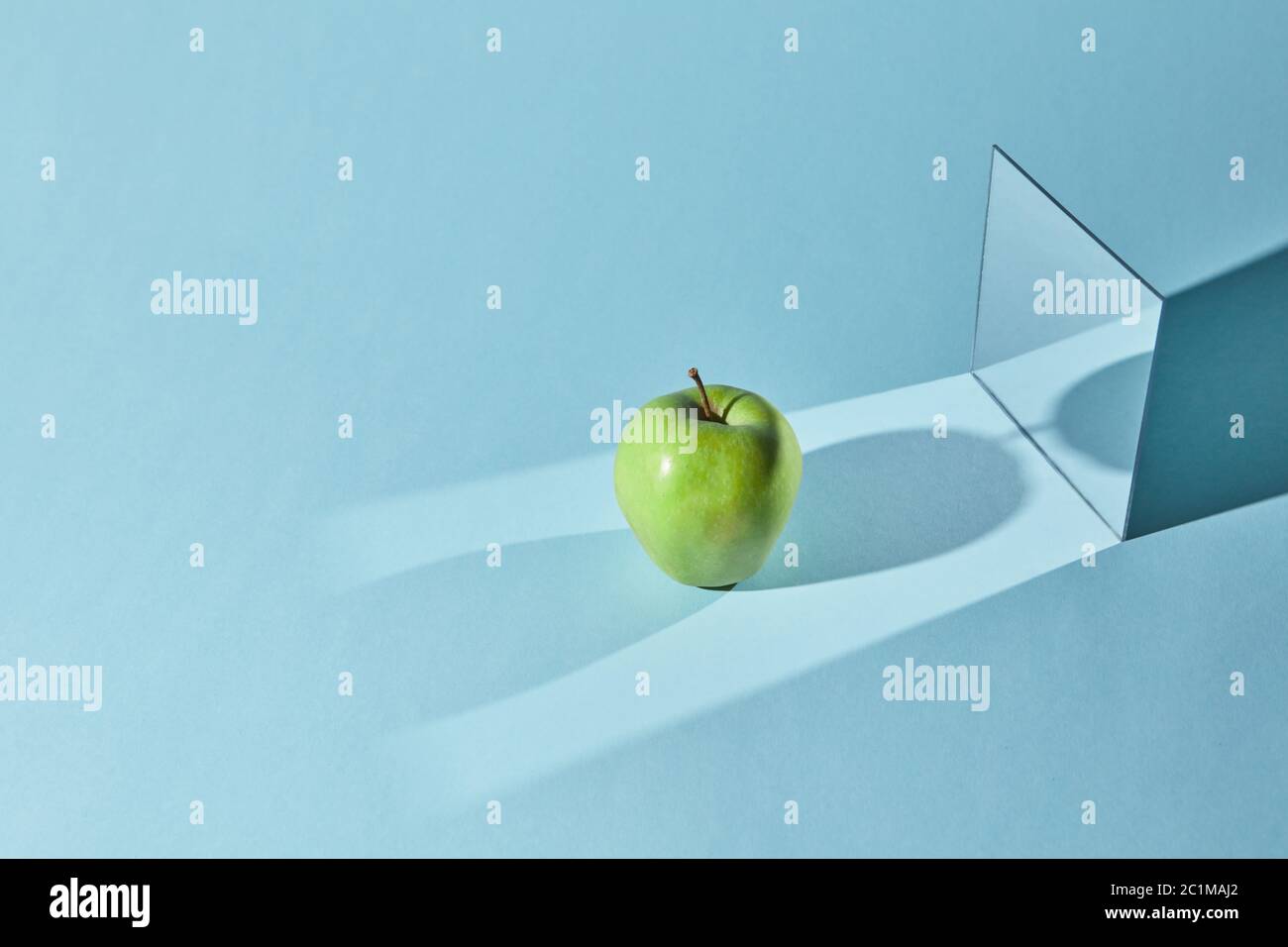La manzana es verde, un espejo cuadrado sobre fondo azul, un reflejo de