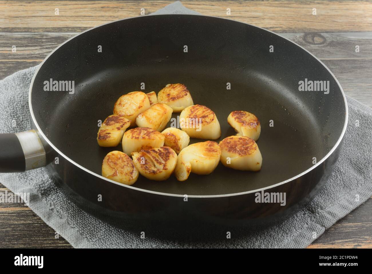 Vieiras salteadas con aceite de oliva en una sartén antiadherente sobre un  paño de cocina sobre una mesa Fotografía de stock - Alamy