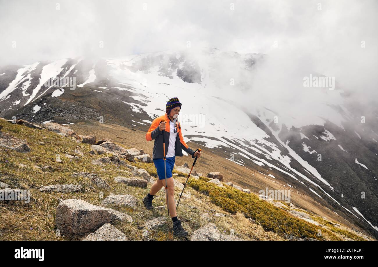 Turista con bastones de trekking es caminar en el valle de montaña en día foggy. Concepto de estilo de vida de actividad al aire libre Foto de stock