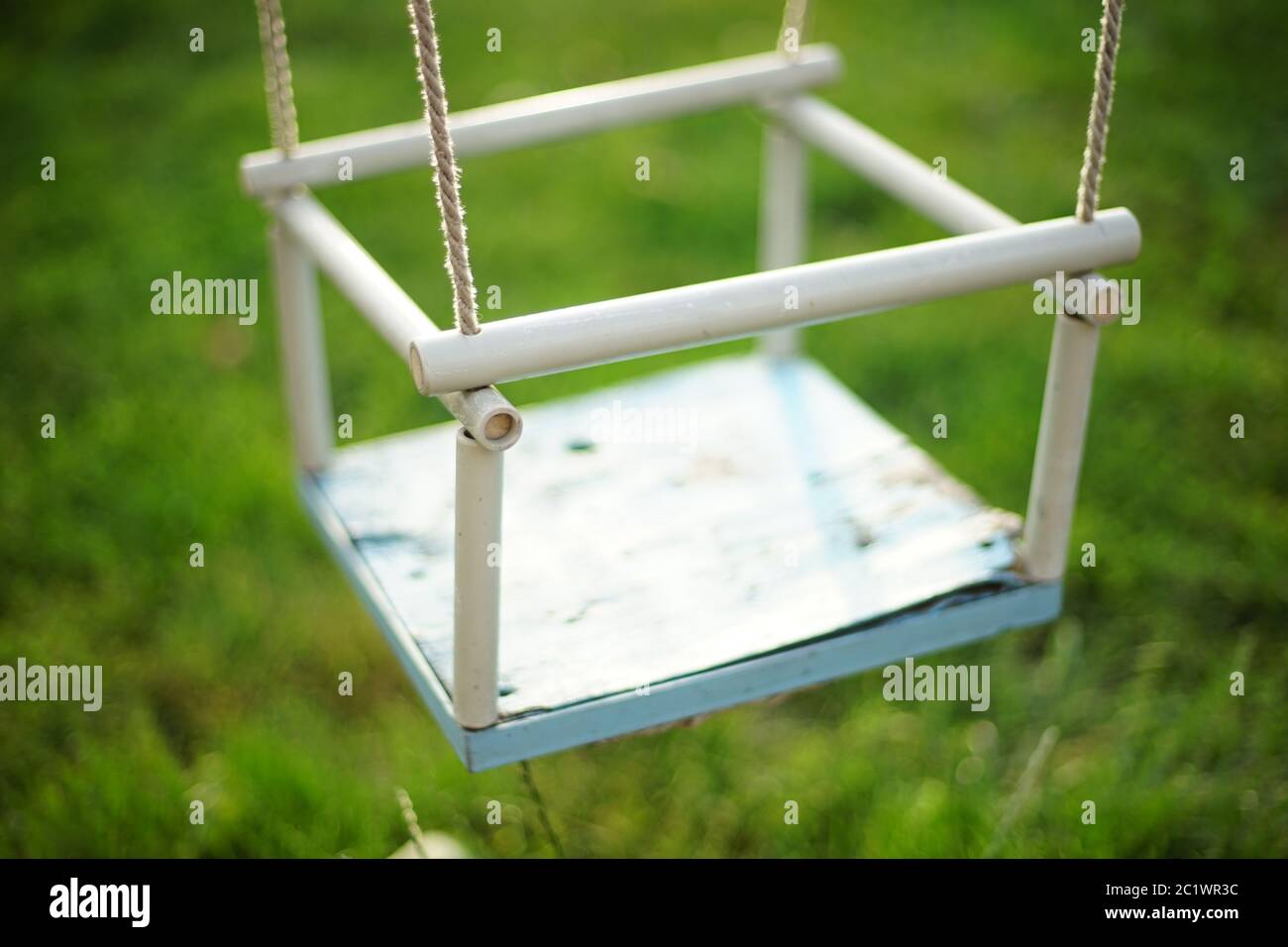 Columpio infantil colgando en las cuerdas en el jardín de verano Foto de stock