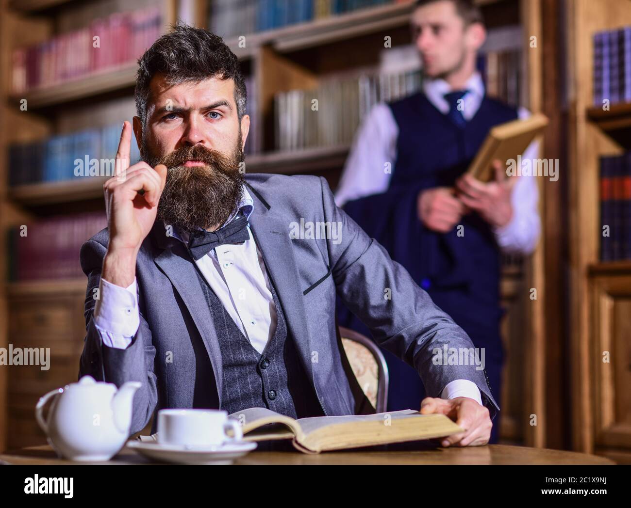Detectives retro trabajan en investigación en sala antigua. Hombres en traje, detectives pasar el ocio en la biblioteca. Concepto de investigador y detective privado. Hombre con barba y cara estricta descubrió acertijo. Foto de stock