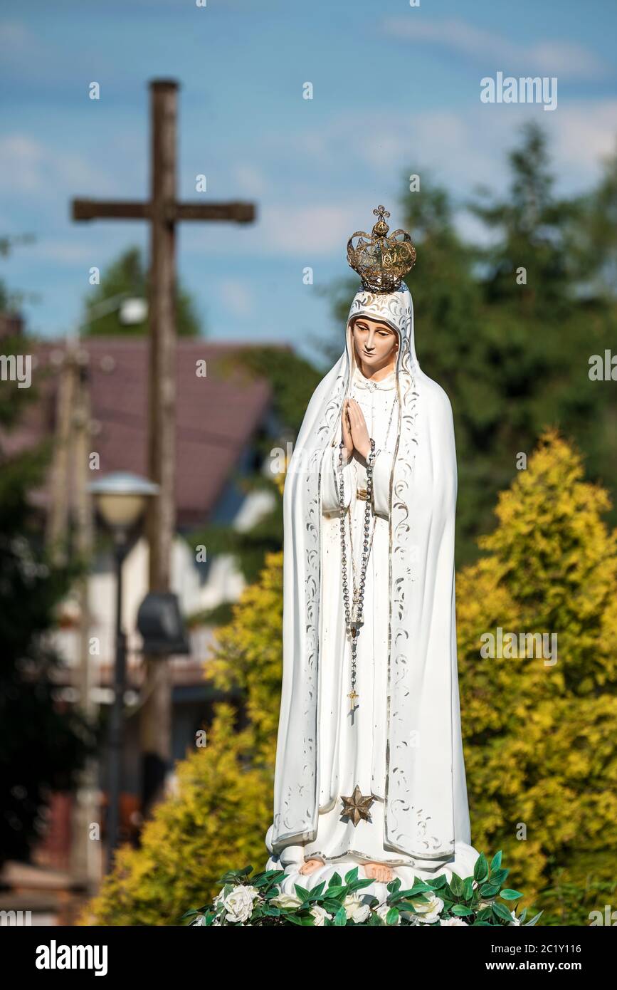 La figura de la Virgen María en la corona con un rosario en sus manos  contra el fondo de plantas verdes en un día soleado Fotografía de stock -  Alamy