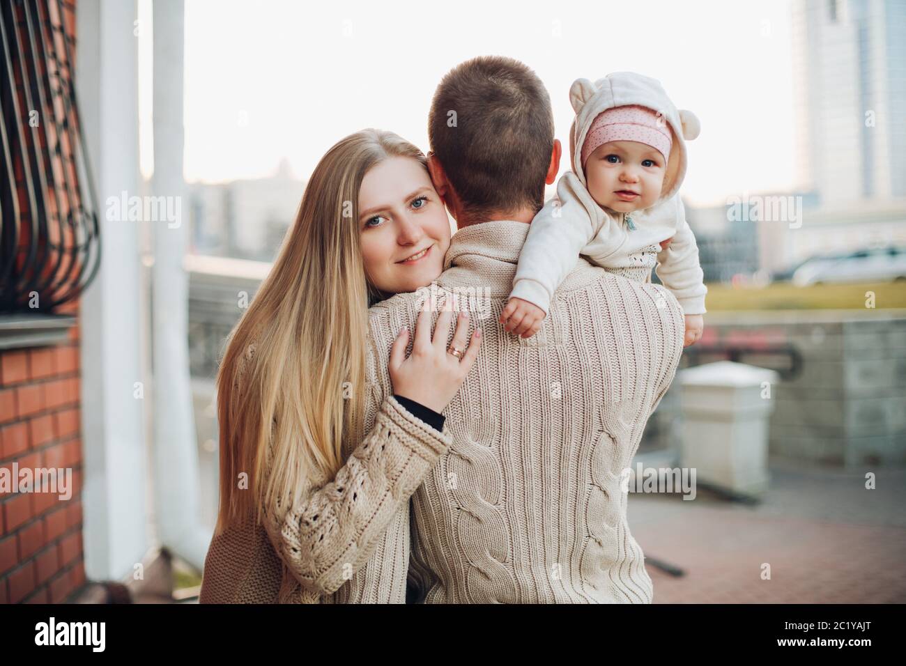 Joven familia feliz sonriendo ante la cámara y juntos. Foto de stock