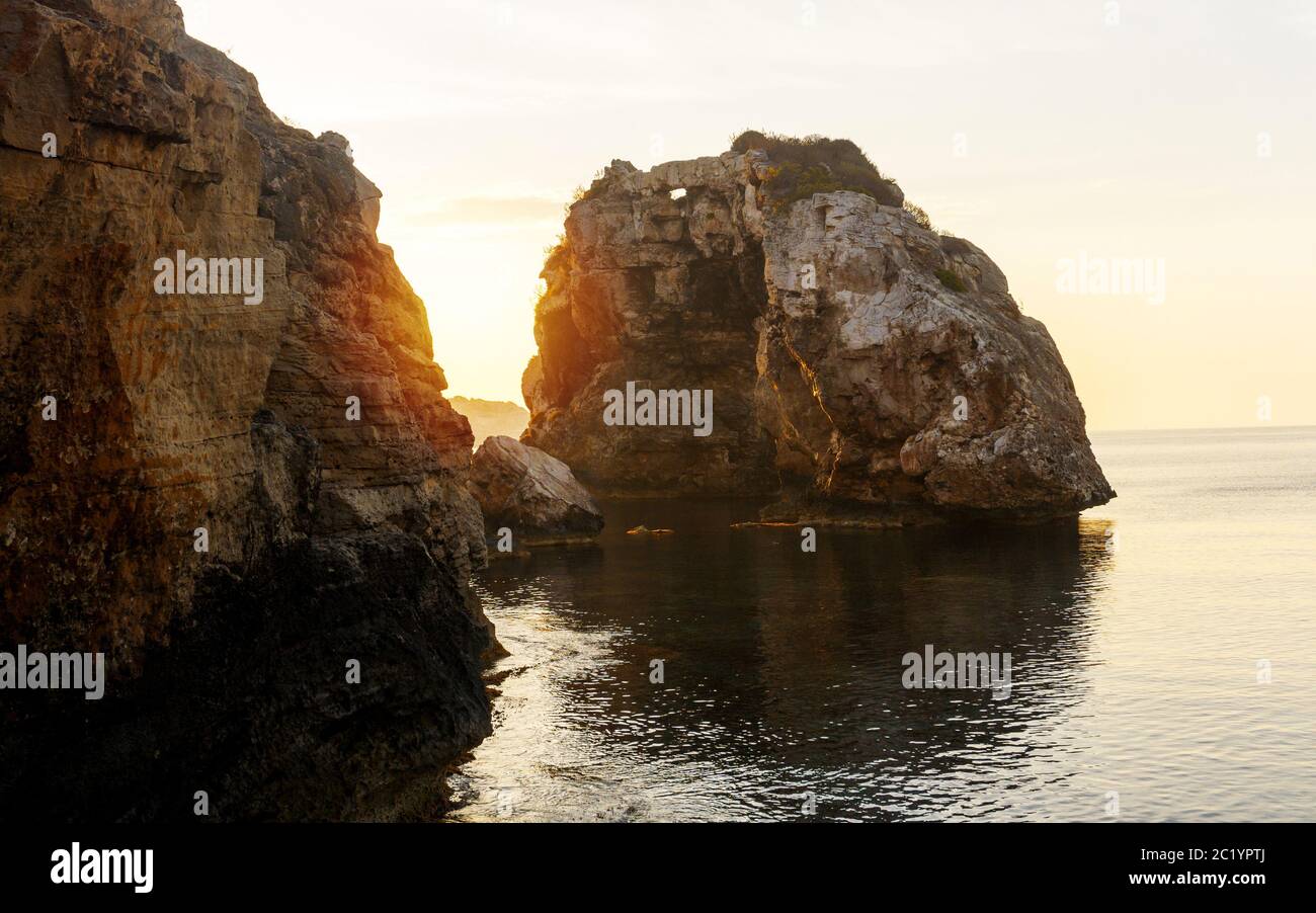 Es Pontas en Mallorca con barco anclado cerca en el mar Mediterráneo. Amanecer con yate y arco de roca cerca de Santanyí Mallorca. Foto de stock