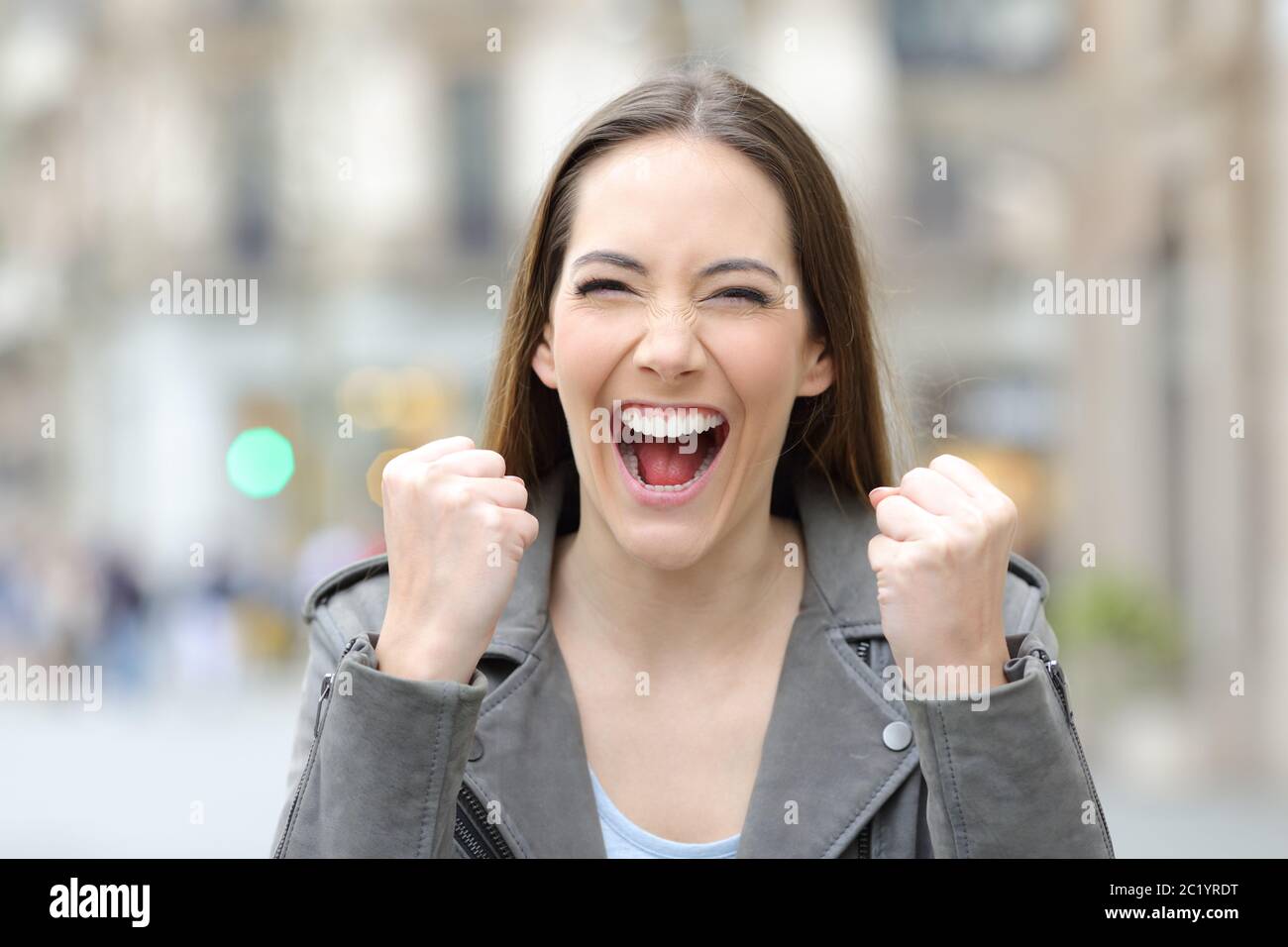 Vista frontal de una mujer entusiasmada celebrando buenas noticias mirando la cámara en la calle Foto de stock