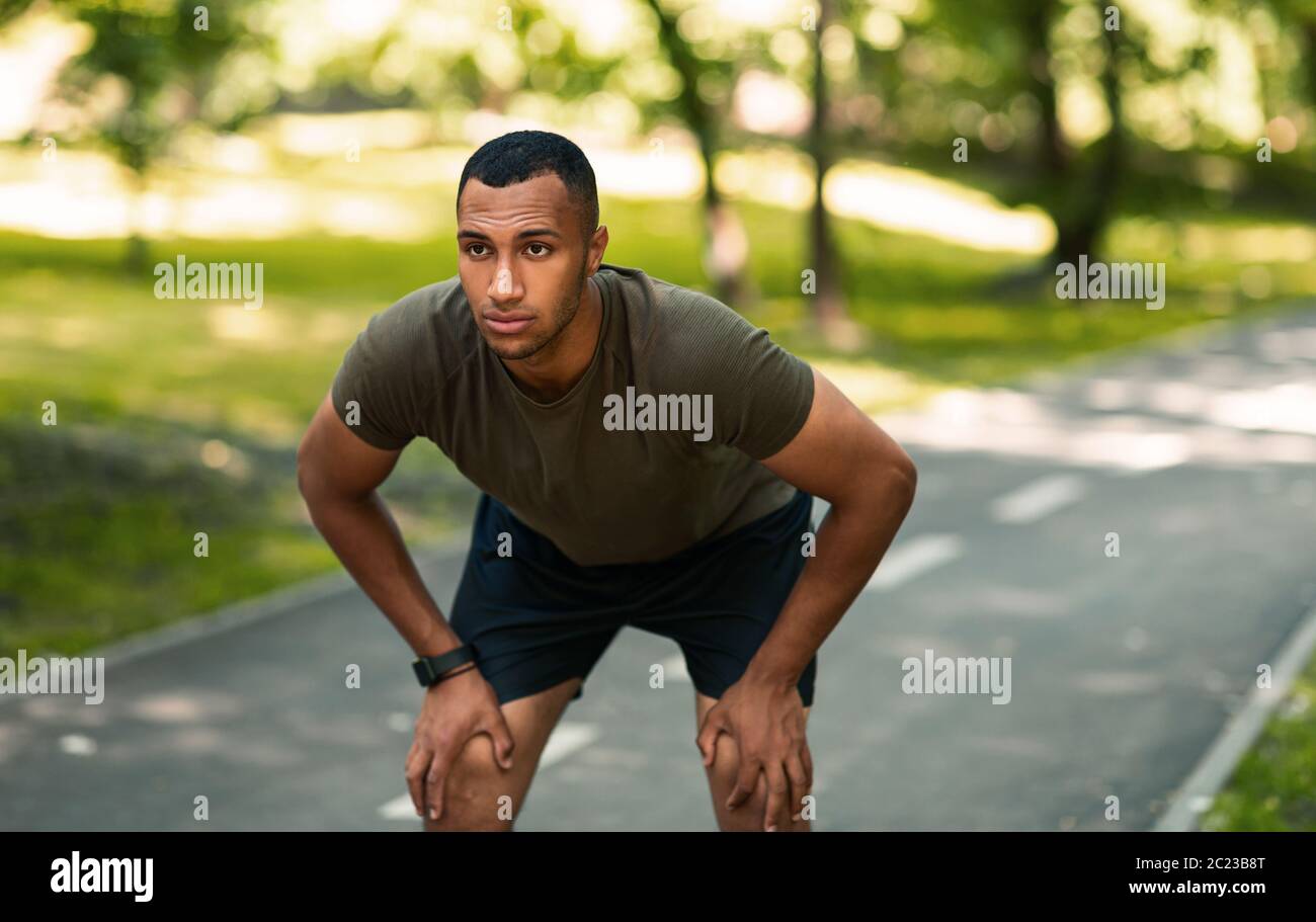 Joven corredor afroamericano tomando descanso después de su entrenamiento en el parque Foto de stock