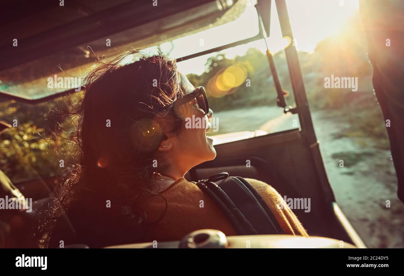 Mujer feliz en safari ride, bonita mujer disfrutando de viaje por Sri Lanka, cabalgando sobre un coche convertible especial y admira la vista sobre los animales salvajes, activo Foto de stock