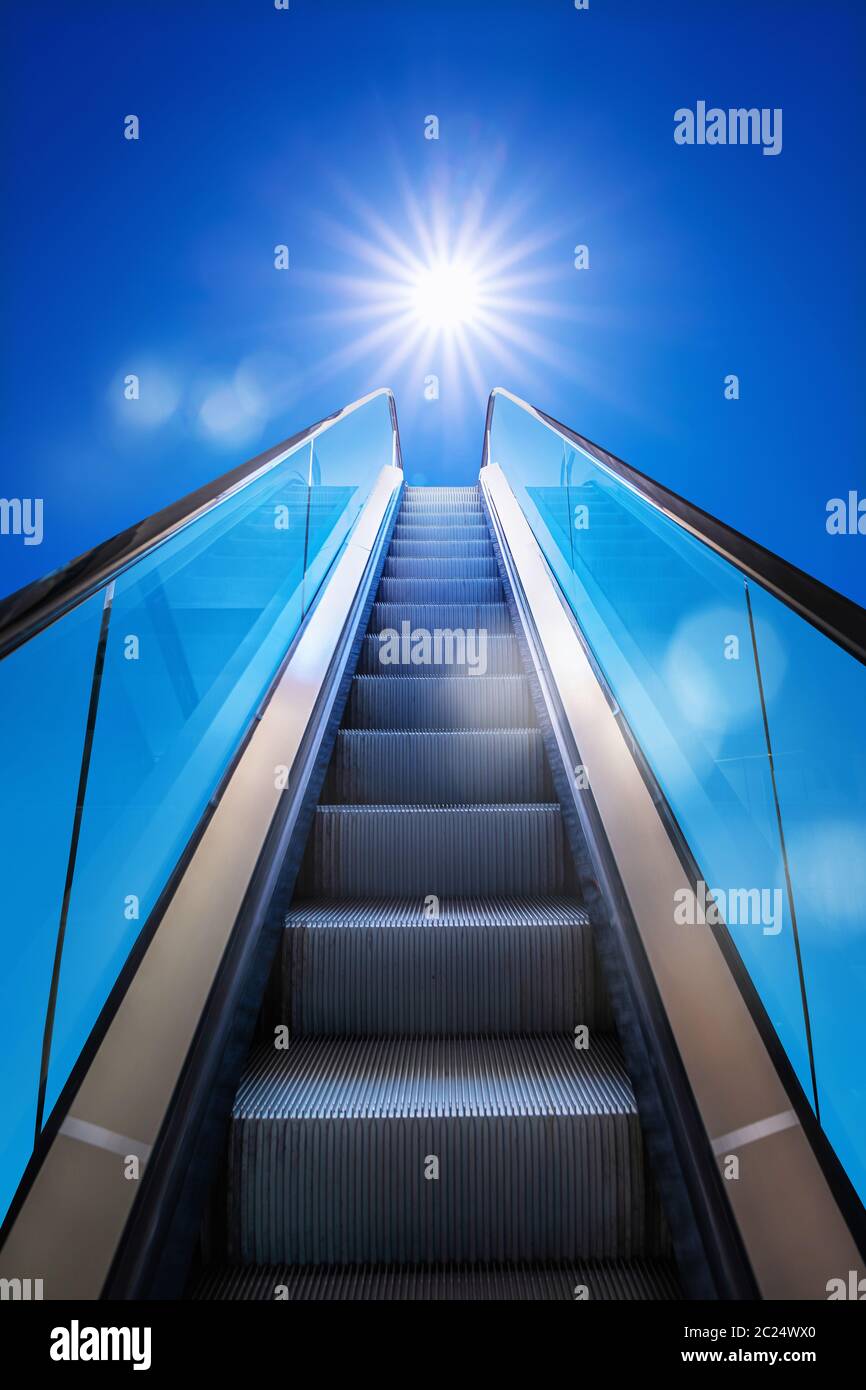 escalera mecánica contra un cielo soleado Foto de stock