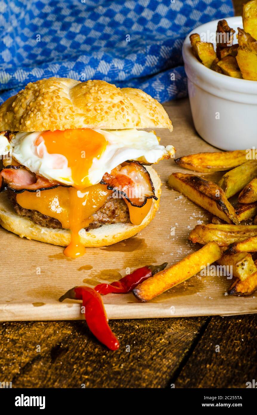 Hamburguesa casera con huevo frito y picante con papas fritas en wood board Fotografía de stock Hamburguesa casera con huevo frito y picante con papas fritas en wood board Fotografía de stock