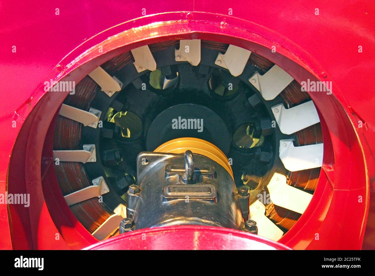 un primer plano del eje de accionamiento y las bobinas de un gran generador industrial rojo Foto de stock