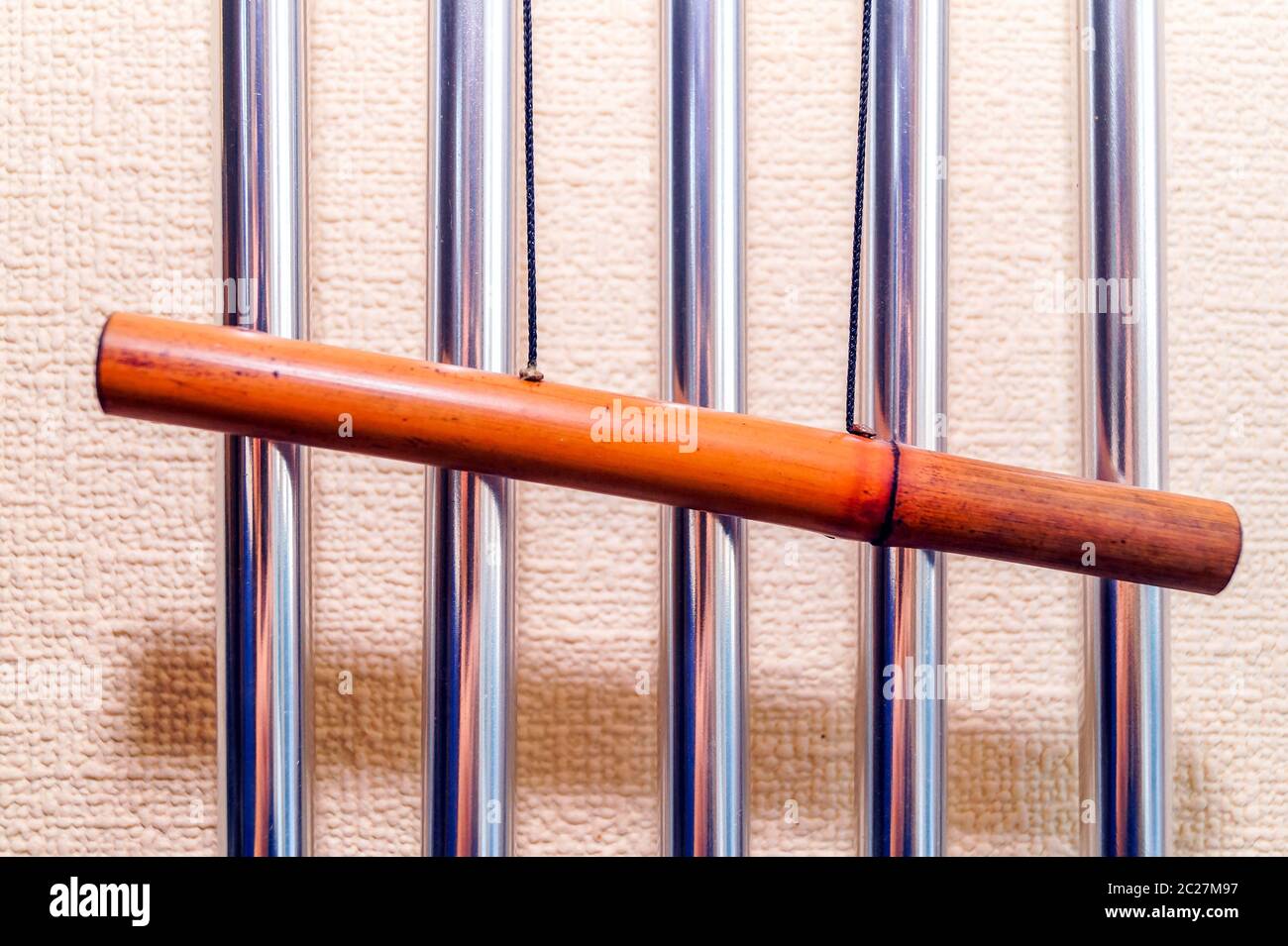 Campanas tubulares metálicas con tubo de bambú cuelgan en la pared y crean la música del viento. Foto de stock