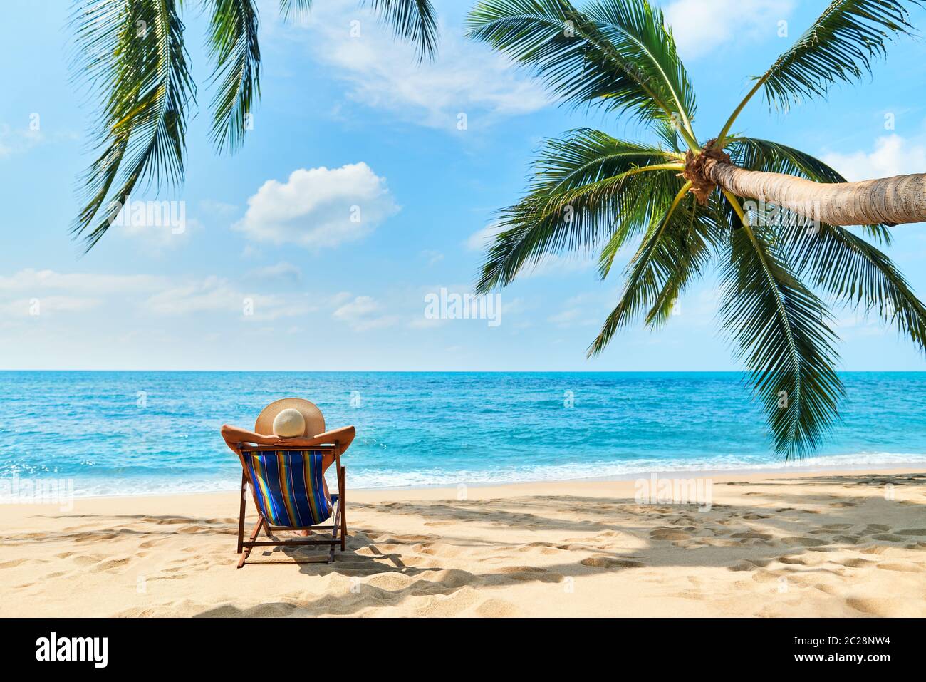Vista trasera de la joven hermosa mujer tomar el sol y relajarse en la playa tropical con espacio para copias Foto de stock