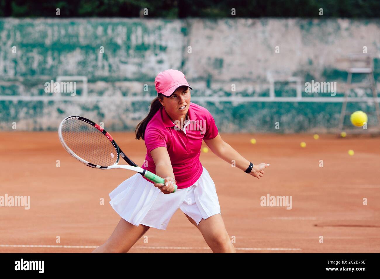 Jugador de tenis. Reproductor femenino vestido en color rosa, falda y blusa  blanca, jugar al tenis en la cancha, listo para golpear una pelota. En  acción Fotografía de stock - Alamy