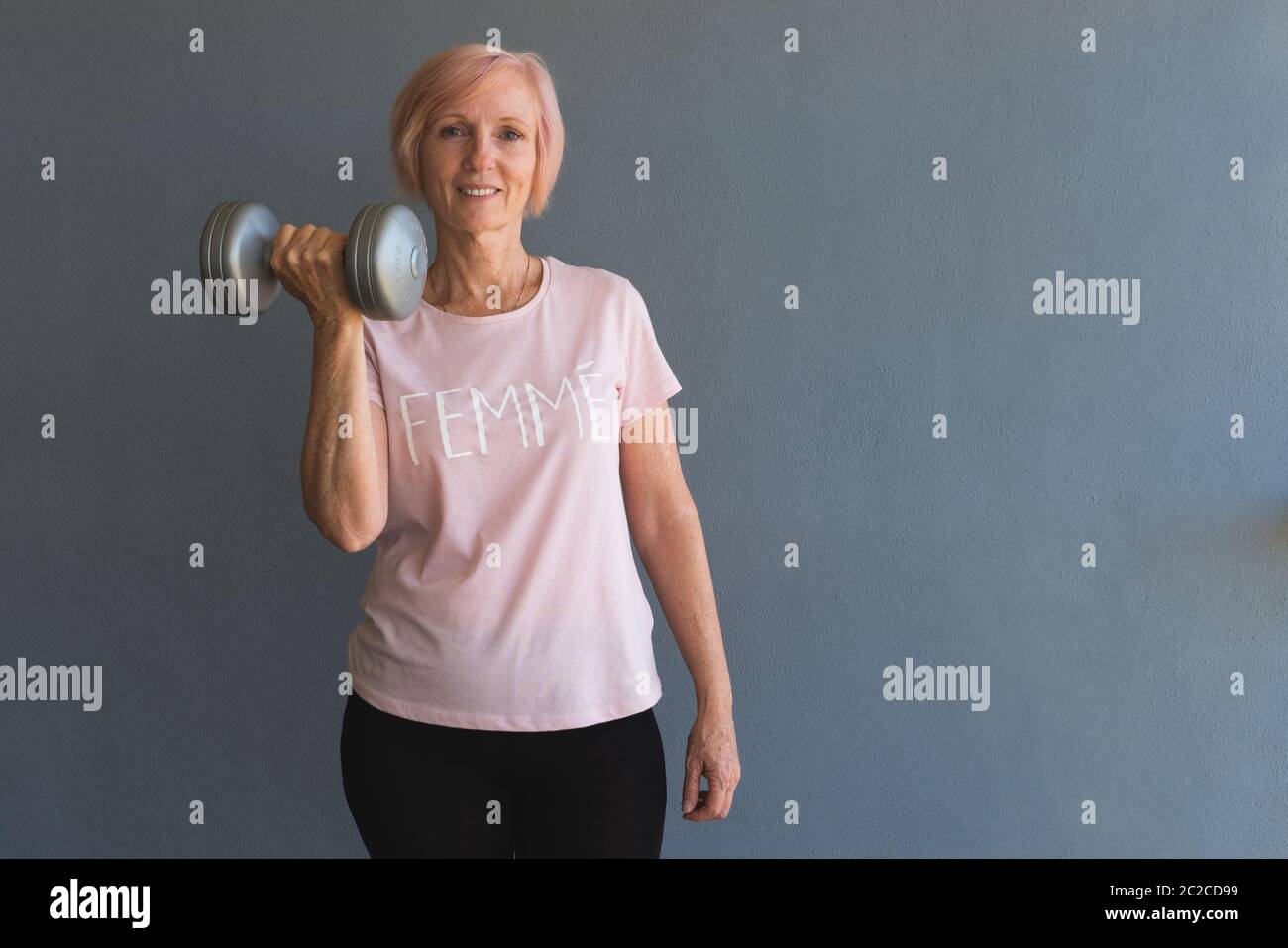 La mujer mayor levantaba pesas y se estaba quedando en forma en casa Foto de stock
