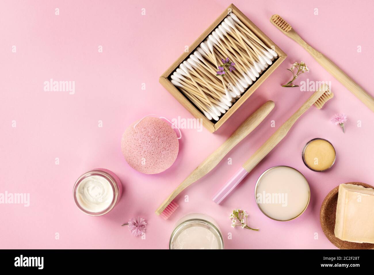 Cosméticos sin plástico, sin residuos, planos sobre un fondo rosa. Cepillos de dientes de bambú y hisopos de algodón, esponja konjac, natural Foto de stock