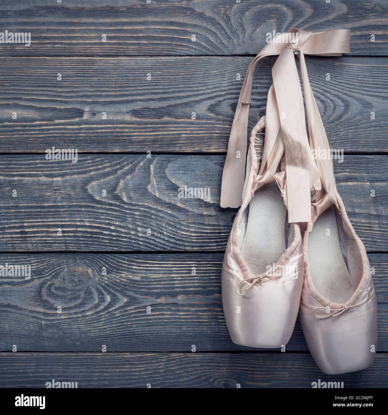 Pointe zapatos zapatos de ballet con un arco de cintas cuelgan de un clavo  sobre un fondo de madera Fotografía de stock - Alamy