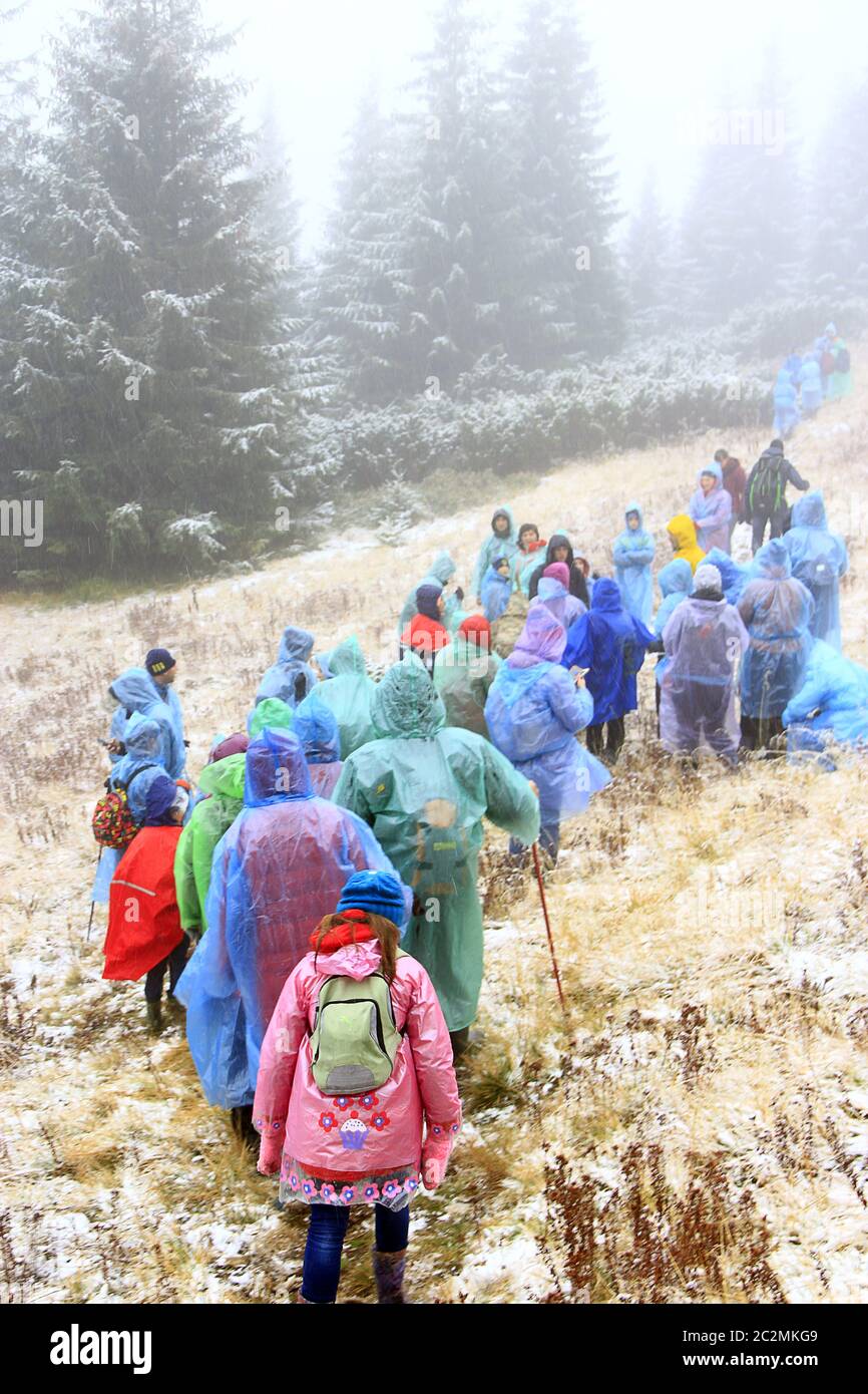 Grupo de turistas en chubasqueros en la caminata en las montañas. Concepto de viaje. Gente que viaja por el bosque Foto de stock