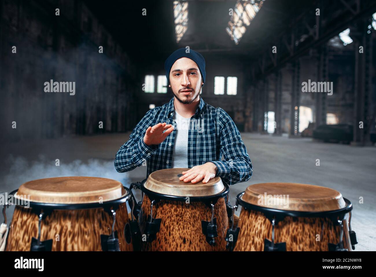 El baterista masculino juega en un tambor de madera en grandes factorías  shop, vista frontal, músico en movimiento. Bongo, instrumento de percusión  musical, la música étnica Fotografía de stock - Alamy