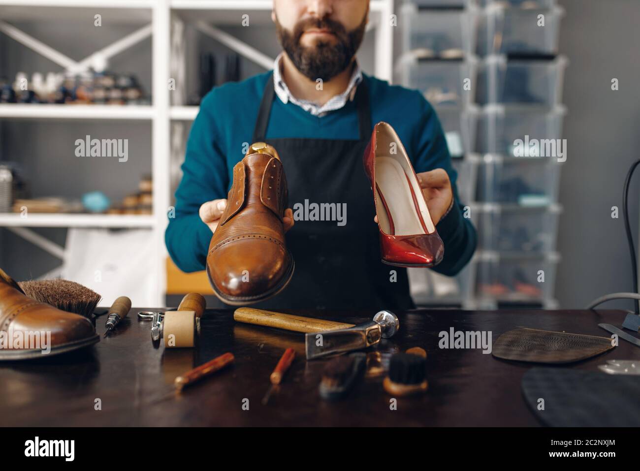 El bootmaker muestra zapatos reparados, servicio de reparación de calzado.  Habilidad artesana, taller de zapatería, obras maestras con botas, zapatero  Fotografía de stock - Alamy