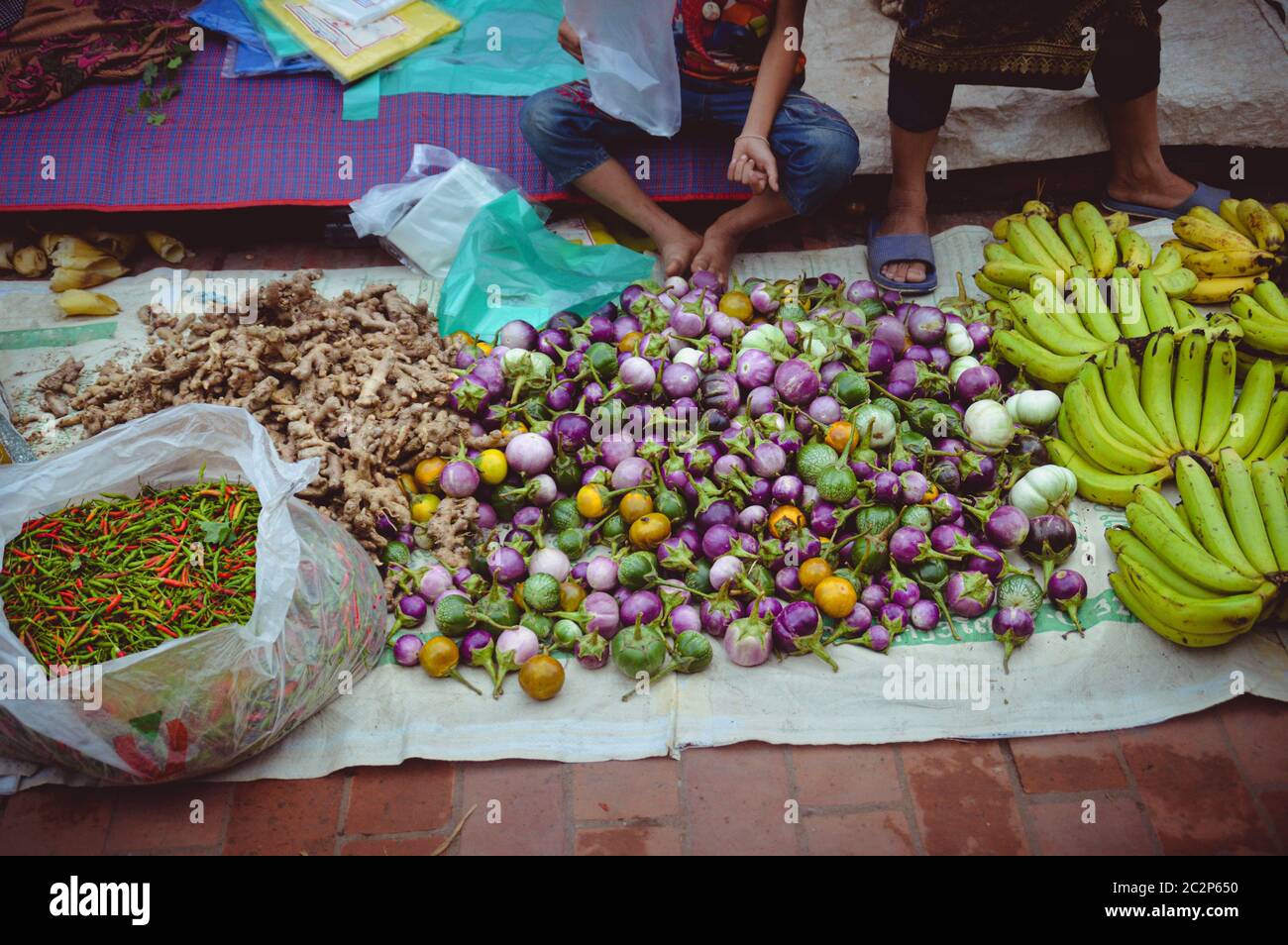 Vendedor callejero que vende verduras frescas en el mercado de la mañana de Luang Prabang En Laos Foto de stock