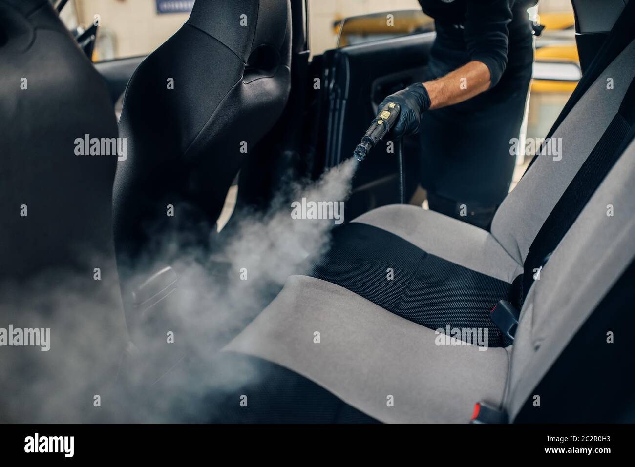 Lavacoches servicio, trabajador masculino en guantes limpia asientos con  limpiador de vapor. Limpieza en seco profesional del interior de coche  Fotografía de stock - Alamy