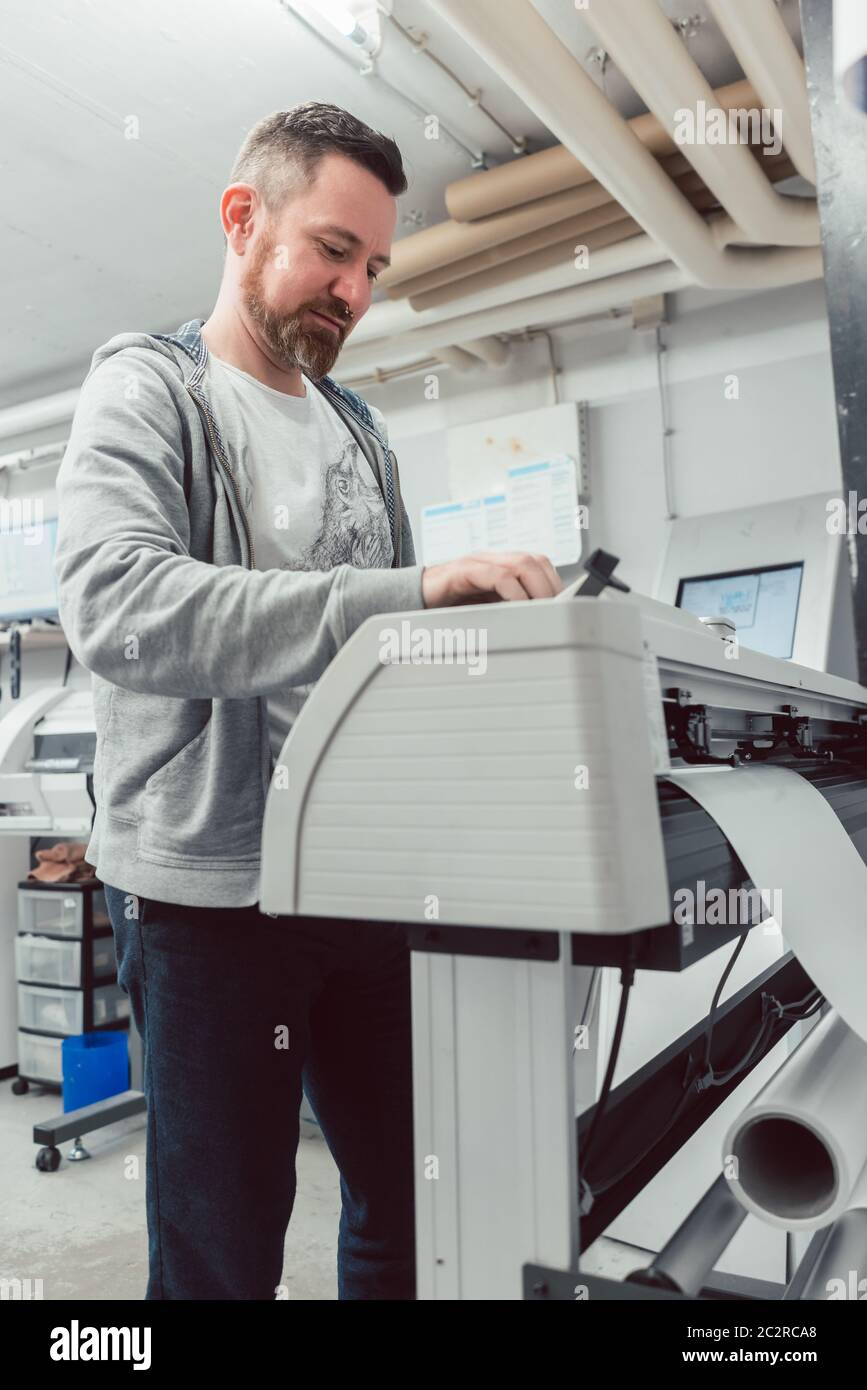 Hombre preparando una impresora de gran formato para un trabajo de  impresión de banner en vinilo Fotografía de stock - Alamy