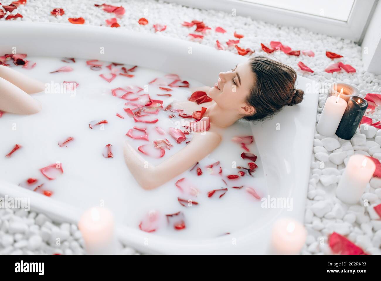 Mujer joven duerme en el baño de espuma, pétalos de rosa y decoración de  velas encendidas. Relajación total, romántico en el baño Fotografía de  stock - Alamy