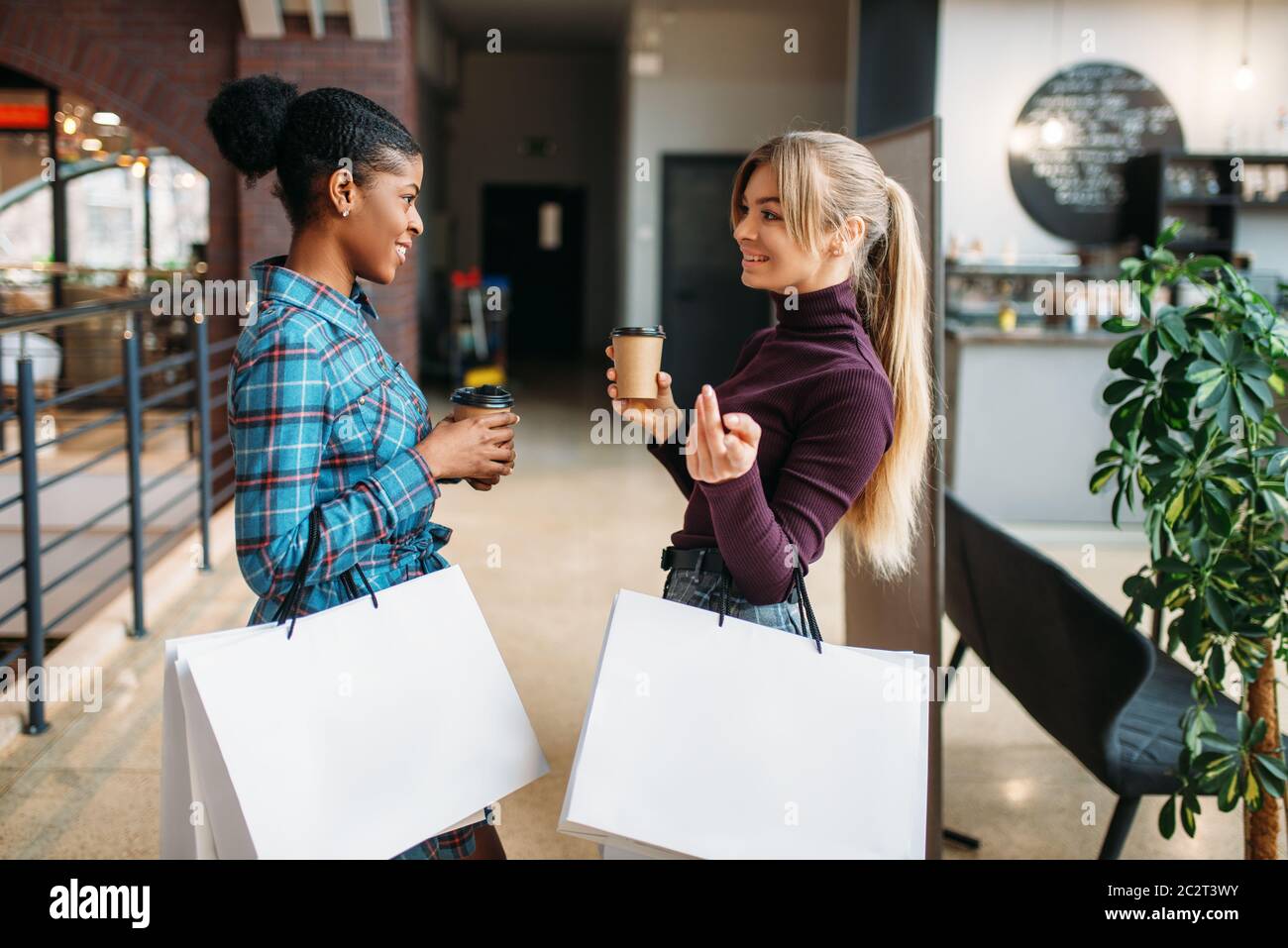 Blanco y negro clientes femeninos con bolsas de compras en el centro comercial. Shopaholics en tienda de ropa, compras, moda Foto de stock