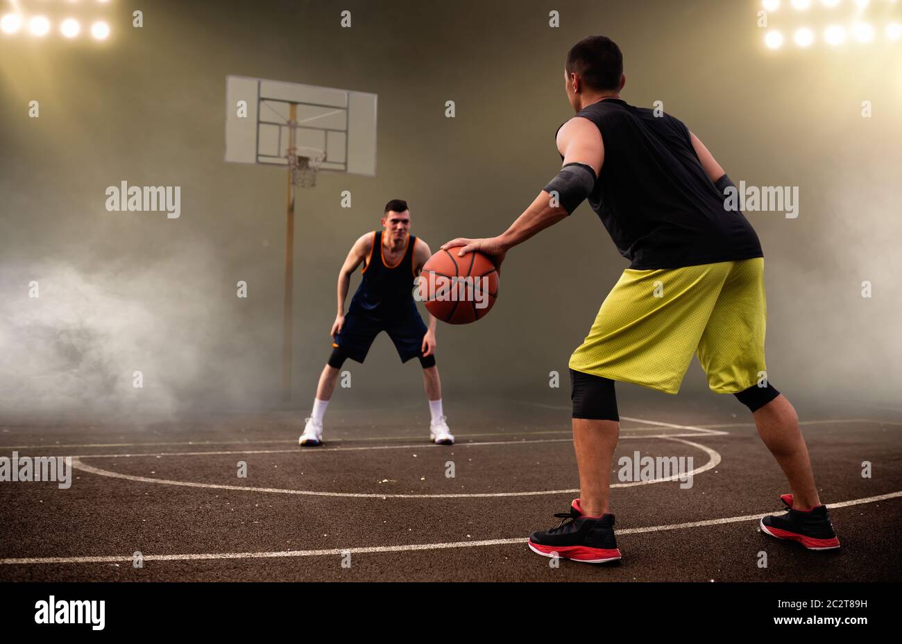 Dos jugadores de baloncesto trabajan tácticas, fondo oscuro. Los atletas  masculinos en sportswear juegan el juego en el entrenamiento de streetball  Fotografía de stock - Alamy