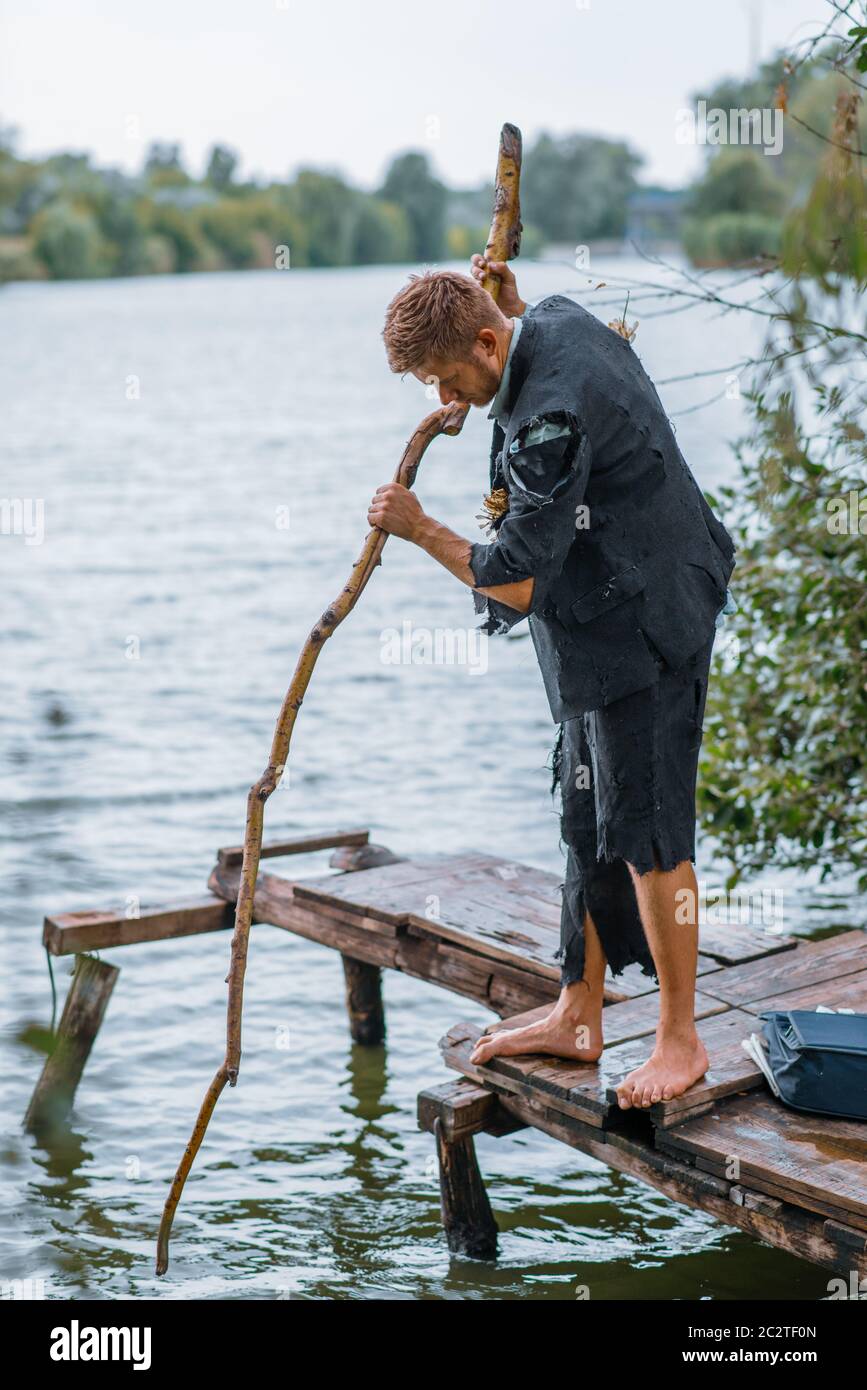 Hombre de negocios en traje de pesca desgarrado en la isla del desierto. Riesgo de negocio, colapso o concepto de bancarrota Foto de stock