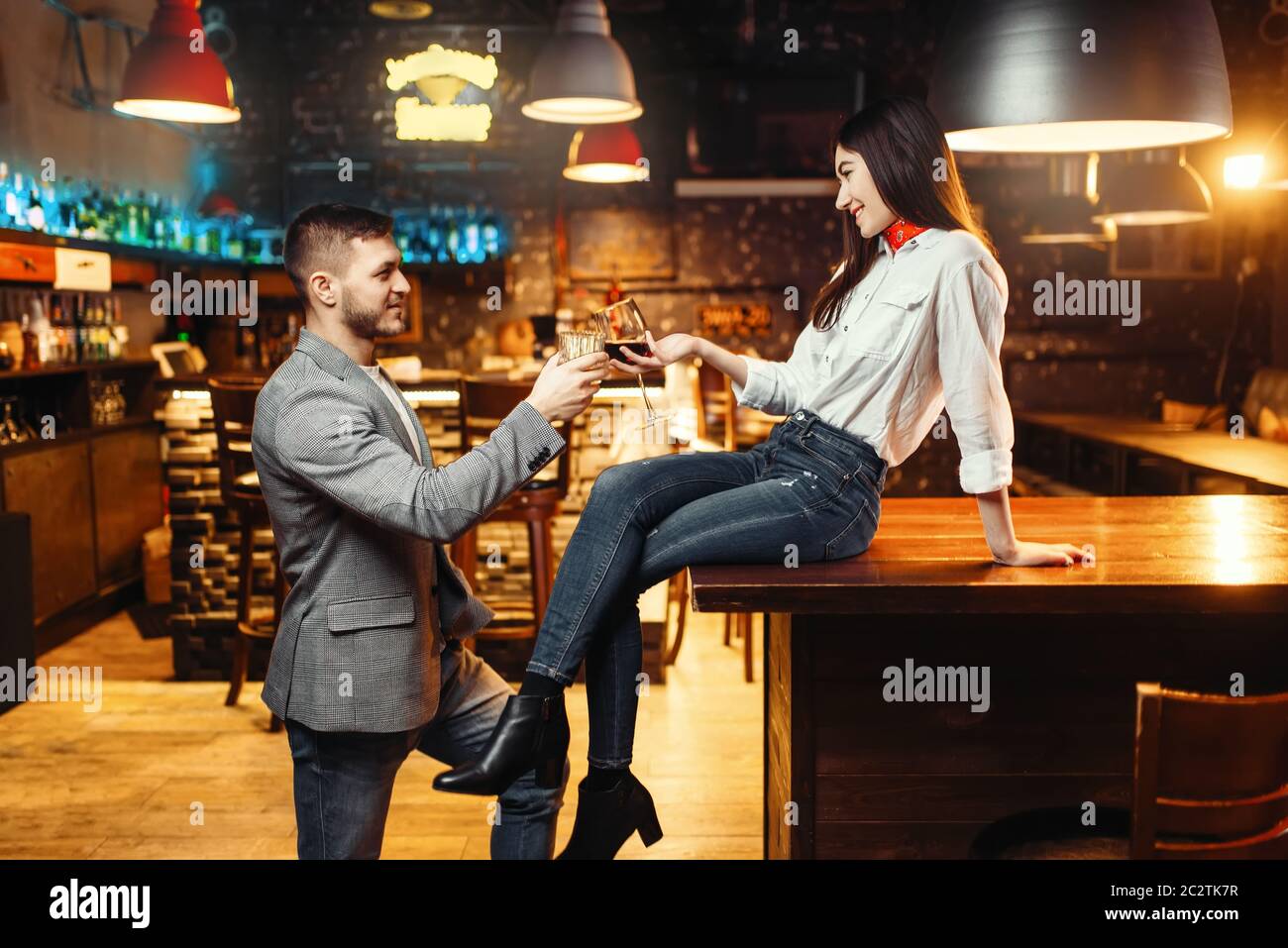 Mujer coqueteando con el hombre, el amor pareja en el mostrador de bar. Los amantes de ocios en el pub, el esposo y la esposa relajándose juntos en discoteca Foto de stock