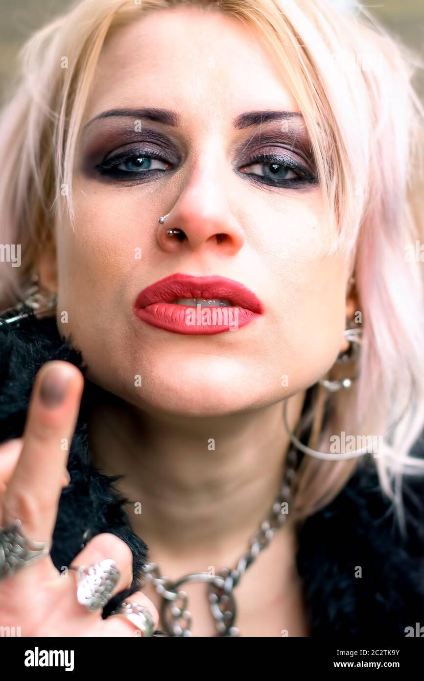 Mujer rubia de estilo punk con perforaciones que muestran el dedo medio  Fotografía de stock - Alamy